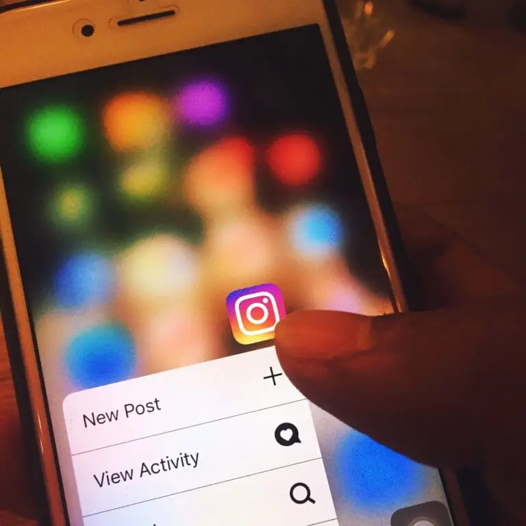 Finger navigating Instagram app on a smartphone screen with colorful blurred background.